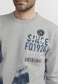 Grau Sweatshirt mit Rundhalsausschnitt, strukturiertem Stoff und buntem Druck mit marineblauen und orangefarbenen Details, einschließlich Logo und Textakzenten.