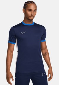 Maglietta atletica blu navy realizzata in tessuto traspirante; presenta accenti blu sul colletto e sulle maniche, con il logo Nike bianco sul petto.