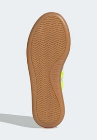 Gum rubber outsole with herringbone pattern, featuring a bright yellow design and textured surface for grip; embossed branding on the heel.