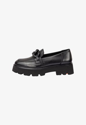 Mocassin à plateforme en cuir noir avec semelle crantée épaisse et bride décorative nouée sur le dessus.