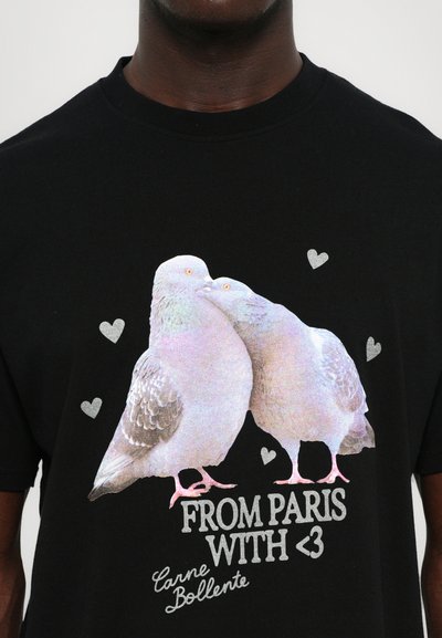 Zwarte T-shirt met een glanzende grafische afbeelding van twee duiven met harten en de tekst "FROM PARIS WITH <3" en "Carne Bollente" in zilveren letters.