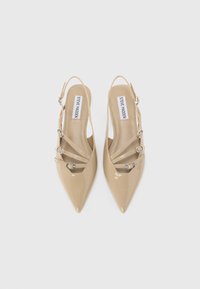 Beige patent leather slingback heels with pointed toes, featuring three decorative straps and silver-tone buckles. Smooth texture and minimal design.
