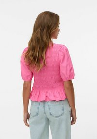 Rosa kortärmad blusas med samlad tyg och peplumslut. Mjuk textur med elastisk smockdetalj på baksidan. Matchas med ljusblå jeans.
