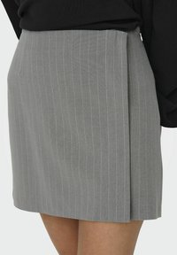Gonna grigia a righe sottili con design sartoriale, caratterizzata da una texture liscia e chiusura con zip laterale. Il tessuto presenta un sottile motivo a righe.