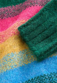 Multicolored knit fabric featuring green, pink, yellow, and blue stripes. Textured wool with a soft, fuzzy finish. Ribbed green cuff.