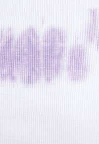 Tejido de algodón con una textura acanalada, principalmente blanco con patrones de tie-dye en lila claro distribuidos de manera desigual por toda la superficie.