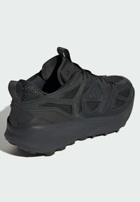 Scarpa sportiva nera realizzata in materiali in rete e sintetici, suola robusta, tallone ammortizzato e dettagli di design con fori unici.