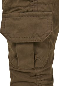 Brune cargo bukser med teksturert stoff, sidelomme med klaff og sømmer for holdbarhet og praktisk design.