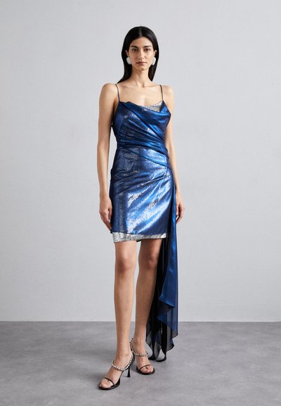Blau metallen glänzendes Minikleid mit drapiertem Design, versehen mit einem silbernen Saum und einem schwarzen transparenten Akzent. Verstellbare Spaghettiträger und eine taillierte Silhouette.