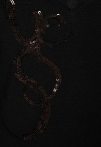 Maglione nero a maglia con un design di paillettes scure in evidenza, realizzato in un motivo di scrittura fluida. Collo a V e texture morbida.