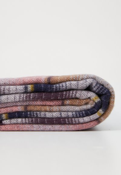 Couverture multicolore, texture douce, enroulée. Présente des rayures en rose, gris, marron et marine avec des motifs subtils et une sensation chaleureuse.