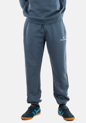 Pantalons de survêtement gris en tissu doux avec une taille élastique, arborant un logo sur la cuisse gauche et des chevilles côtelées.