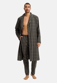 Ruitjesbadjas en bijpassende broek in donkergroen met blauwe lijnen; de badjas heeft een losse pasvorm en een open voorkant, de broek heeft een elastische tailleband.