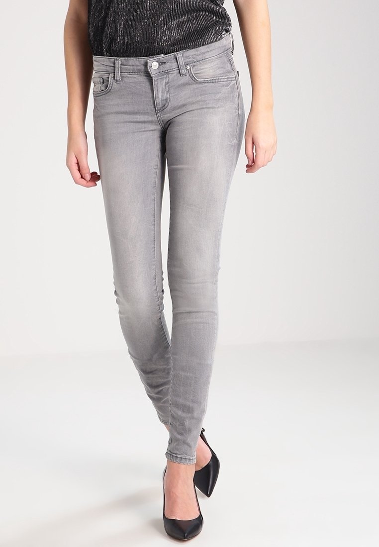 Jeans gris ajustados hechos de mezclilla, con un diseño de tiro medio y cinco bolsillos, y un leve desgastado, combinados con tacones altos negros.
