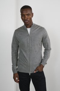 Grå zip-up tröja tillverkad av mjukt tyg, med hög krage, långa ärmar och en slät yta, kombinerad med mörka byxor.