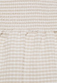 Beige textil med vertikal smockning upptill och ett rutigt mönster nedanför, med växlande vita och beige ränder.