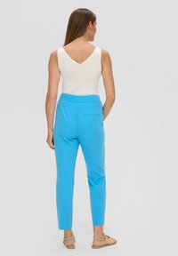 Lichtblauwe op maat gemaakte broek met een vlakke tailleband en een slim fit, gecombineerd met een witte mouwloze top met een V-hals ontwerp.