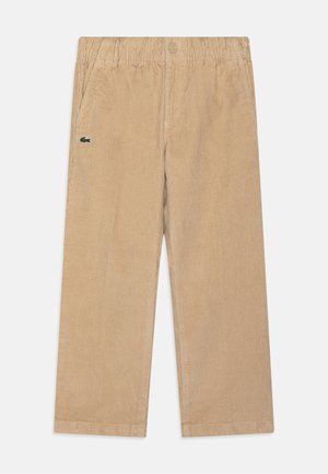 Beige corduroy broek met een elastische tailleband, voorzien van zijzakken en een klein groen geborduurd logo op de linker bovenbeen.