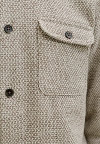 Camicia button-up a quadratini marrone e crema realizzata in tessuto testurizzato, con taschino e bottoni marroni.