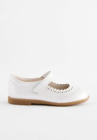 Weiße Leder-Mary-Jane-Schuhe mit gewelltem Rand, verstellbarem Riemen und einer beigen Gummisohle. Mit durchbrochener Verzierung an der Zehenpartie.