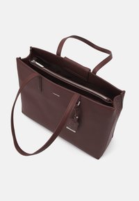 Burgundy läder tote-väska med dragkedja, två handtag och en dekorativ tagg. Slät yta med en subtil präglad logotyp på ena sidan.
