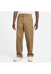 Bruna, löst sittande byxor med rak front, tillverkade av tyg. Har en Nike-logga på vänstra låret och en klassisk midjebandsdesign.