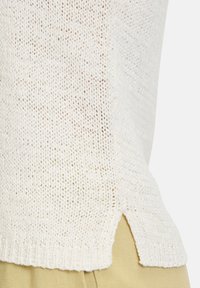 Maglione lavorato a maglia in bianco sporco, con texture a punto aperto, spacchi laterali e orlo a coste. Il design è a vestibilità rilassata con un finish casual.