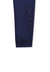 Jogger azul marino con cintura elástica, puños acanalados y un logotipo texturizado de DKNY en negro mostrado de forma prominente en el costado.