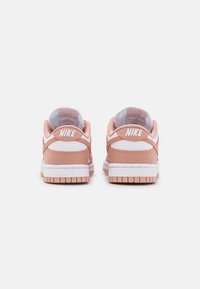 Nike Dunk sneakers featuring a pale pink leather upper, white accents, padded collar, and a textured rubber outsole.