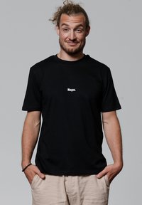 Schwarzes Baumwoll-T-Shirt mit kurzen Ärmeln und rundem Halsausschnitt, auf dem der Text "Nope." in Weiß, zentriert auf der Brust, steht.