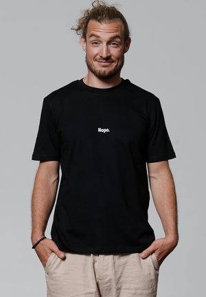 Zwarte katoenen t-shirt met korte mouwen en een ronde halslijn, waarop de tekst "Nope." in het wit, gecentreerd op de borst.