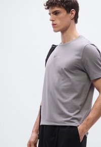 Γκρι βαμβακερό μπλουζάκι με στρογγυλή λαιμόκοψη και κοντά μανίκια. Διαθέτει διακριτικό λογότυπο "BOSS" στο κέντρο. Λείο ύφασμα, άνετη εφαρμογή.