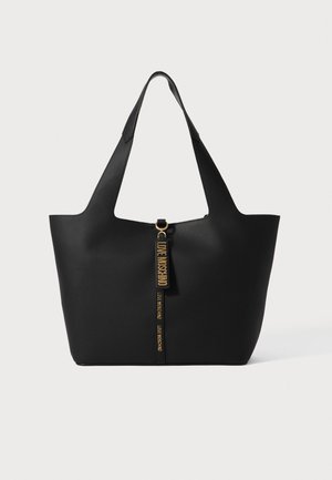 Juodas minimalistinio dizaino šantinis krepšys, pagamintas iš lygaus medžiagos. Įrengtas auksiniu užtrauktuko traukikliu su prekės ženklo etikete ir dviem tvirtais rankenų.