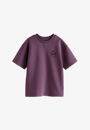 Lila Baumwoll-T-Shirt mit kurzen Ärmeln, das auf der linken Brust ein kleines schwarzes Totenkopfdesign mit Kopfhörern zeigt. Runder Halsausschnitt.