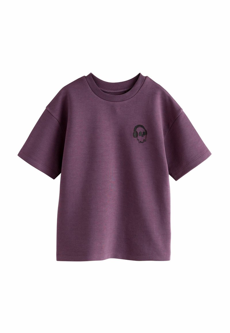 T-shirt di cotone viola a maniche corte, con una piccola grafica di un teschio nero con cuffie sul lato sinistro del petto. Collo rotondo.