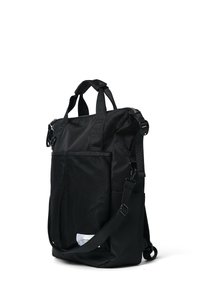 Svart nylon tote-väska med en texturerad mesh-fickan fram, dubbla handtag upptill och en justerbar axelrem. Dragkedjestängning högst upp.