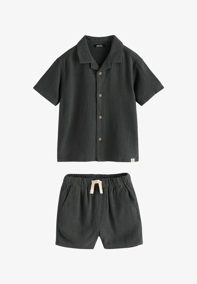 Chemise gris foncé à manches courtes avec boutons et col, accompagnée d’un short assorti à cordon et poches, posés à plat sur fond blanc.