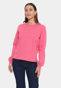Felpa di cotone rosa con maniche lunghe, scollatura tonda e ricamo del logo "Smile" sulla parte frontale. Presenta una vestibilità comoda e spacco laterale.