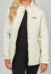 Vadderad krämfärgad jacka av slätt material, med guldfärgade detaljer, dragkedja och tryckknappar, samt sidofickor.