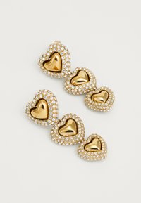 Orecchini a forma di cuore in tonalità oro con un centro liscio in oro circondato da rhinestones trasparenti, caratterizzati da una finitura texturizzata luccicante.