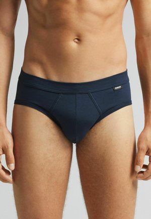 Navyblauwe slips van rekbaar materiaal, met een brede tailleband, een soepele textuur en een gestructureerd ontwerp aan de voorkant.