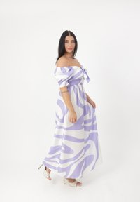 Abito maxi off-the-shoulder bianco con audaci motivi astratti in lavanda; presenta una vita arricciata e un dettaglio a fiocco sul davanti.