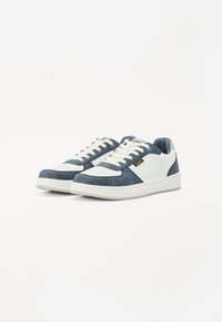 Zapatillas de ante azul y cuero blanco con lengüeta acolchada, cordones planos y suela de goma texturizada. Acento del logo dorado en el lateral.