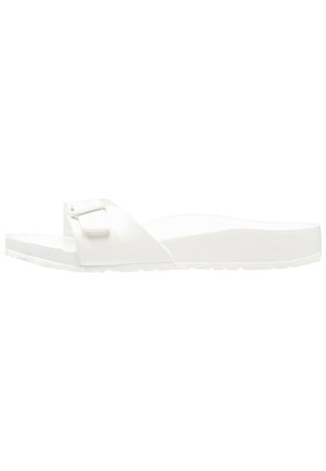 Valged liug-sandalid ühe reguleeritava rihmaga, millel on tekstuuriga pind, lame tall ja minimalistlik disain mugavuse tagamiseks.