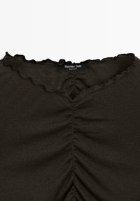 Top marrone scuro con scollatura a V, texture arricciata e bordi scallop. L'etichetta del marchio "Massimo Dutti" è visibile all'apertura.