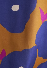 Tessuto con grandi motivi floreali blu su uno sfondo senape con accenti rosa. Texture liscia con una leggera lucentezza.