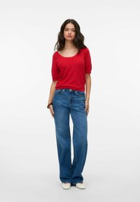 Punane ribaga lühikeste varrukatega T-särk laia kaelusega, mis on partnered helesiniste laia jala teksade ja kreemjate slip-on kingadega. Sile tekstuur.