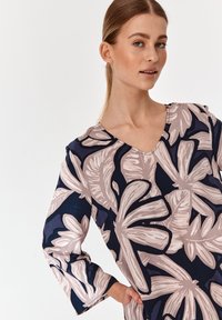 Langärmliges Kleid mit navyfarbenem Hintergrund und großen, hellrosa Blumenmustern. V-Ausschnitt-Design mit weicher Textur und lässiger Passform.