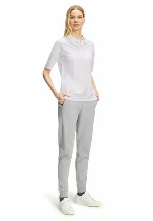 T-shirt polo blanc à manches courtes, associé à un pantalon de survêtement gris clair, doté de poches latérales et de poignets, complété par des baskets blanches.