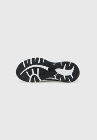 Black and white athletic shoe sole with deep grooves and tread patterns for traction, shown against a plain white background.